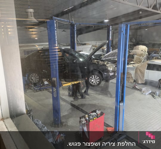 מוסך עם רכב על ליפט, מכסה מנוע פתוח